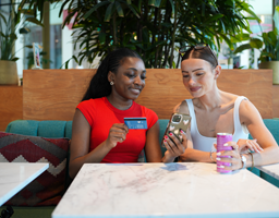 Deux femmes payent avec leur carte sur un smartphone